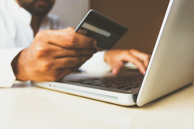 Man holding a credit card while also on his laptop