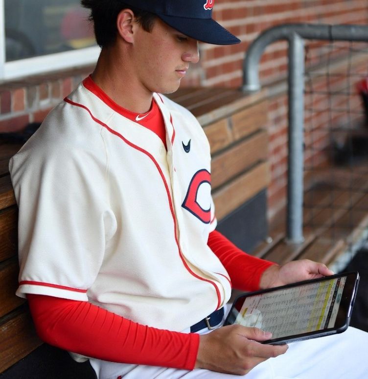 collegiate baseball pitcher reviewing stats on a tablet in a dugout